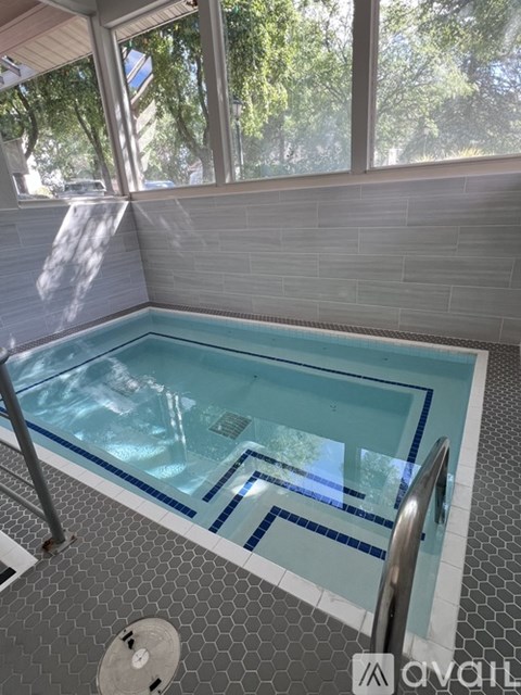 A swimming pool with a blue tiled edge and a grey tiled floor.