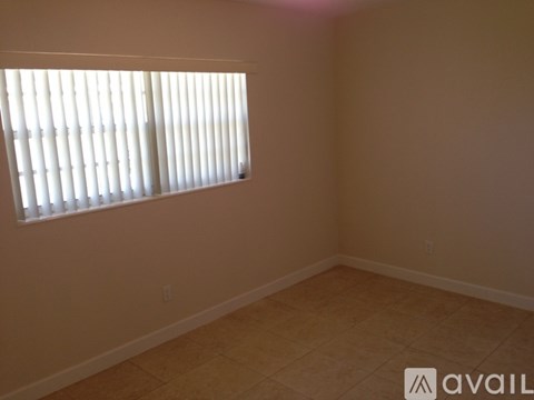 A room with a window covered by white blinds.