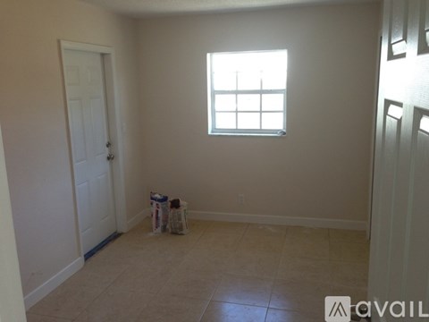 A room with a white door, a window, and a trash can.