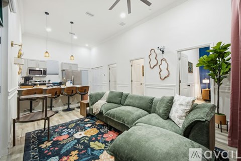 A living room with a green couch and a floral rug.