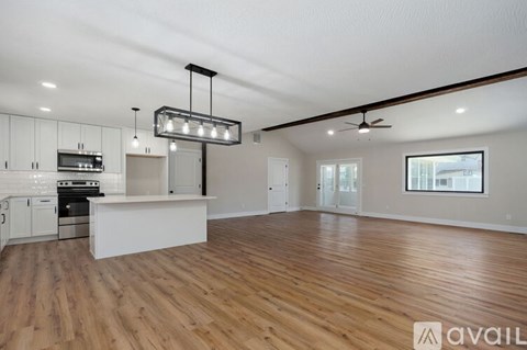 A spacious kitchen with white cabinets and a wooden floor.