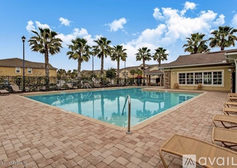 A pool surrounded by palm trees and lounge chairs.