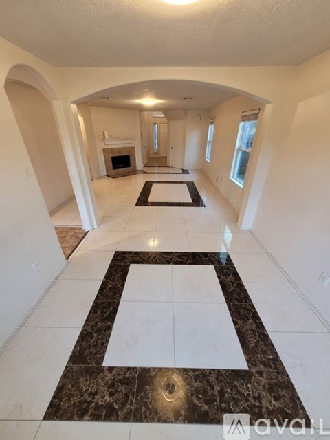 A hallway with a marble floor and a fireplace.