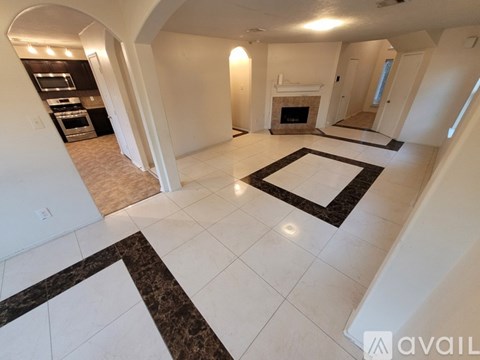 A spacious living room with a fireplace and a kitchen area in the background.