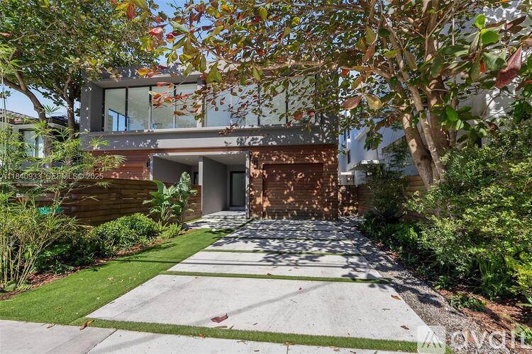 A modern house with a glass door and a driveway.