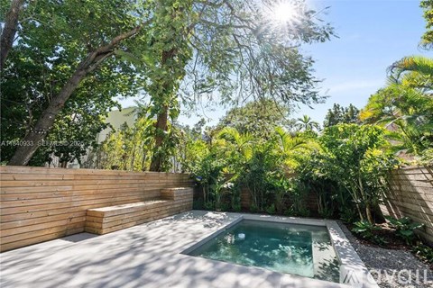 A small pool surrounded by trees and wooden fencing.