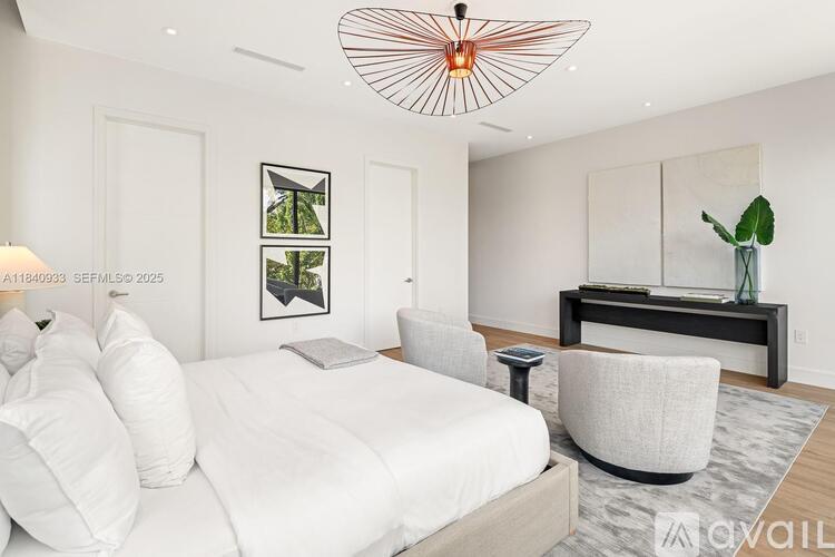 A modern bedroom with a large bed and a white chair.