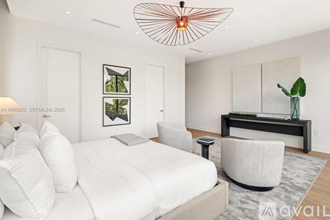 A modern bedroom with a large bed and a white chair.