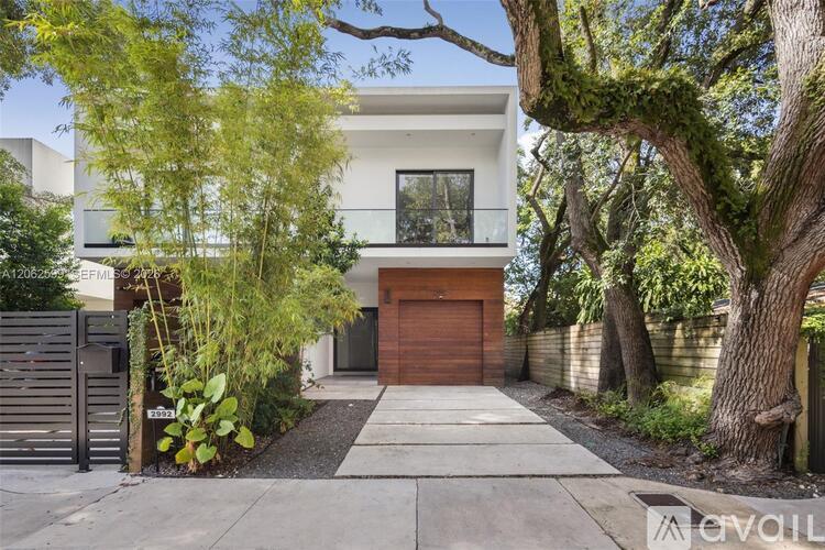 A modern house with a brown garage door is surrounded by greenery.