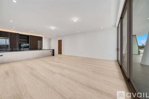A spacious room with wooden flooring and a large window on the right side.