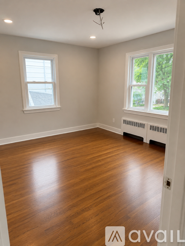 A room with wooden floors and two windows.