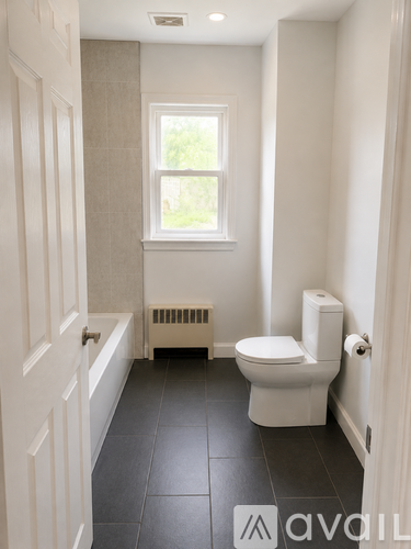 A white toilet in a bathroom with a window.
