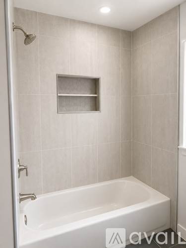A white bathtub in a bathroom with a shower head and a shelf above it.