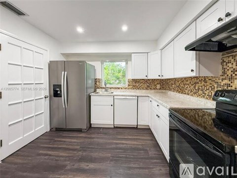 A kitchen with white cabinets and a black countertop.