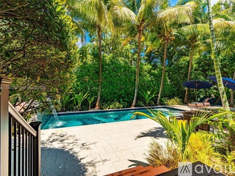 A pool surrounded by palm trees and a deck.