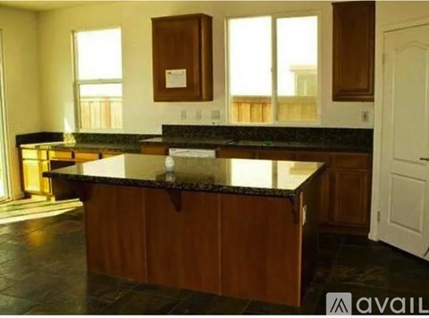 A kitchen with a granite countertop and wooden cabinets.