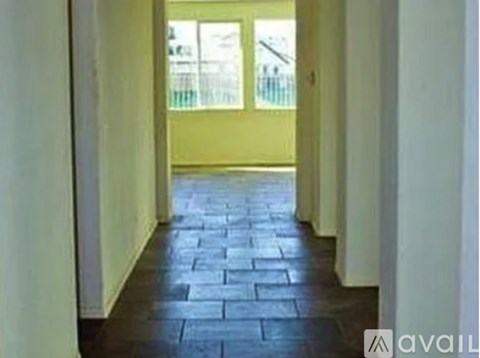 A hallway with a black stone floor and white walls.