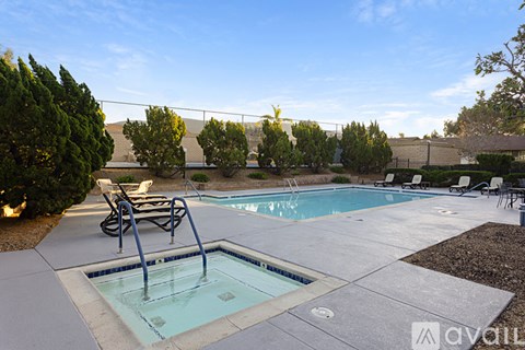A pool surrounded by trees and chairs.