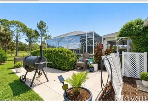 A backyard with a grill and a white lattice fence.