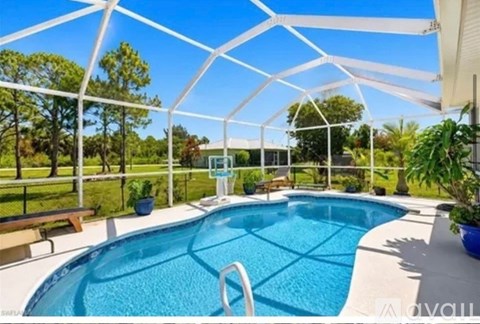 A pool under a white canopy with trees in the background.
