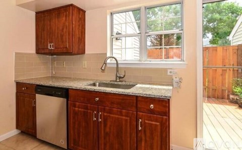 A kitchen with wooden cabinets and a stainless steel dishwasher.