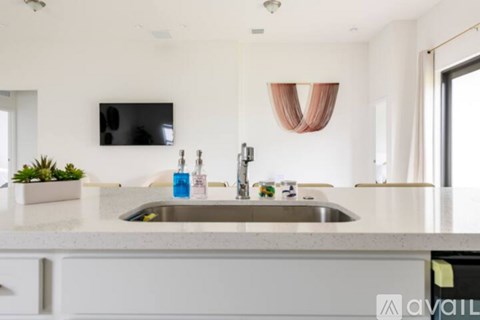 A modern kitchen with a sink and a flat screen TV mounted on the wall.