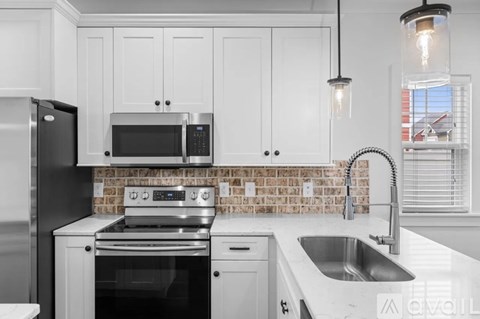 A kitchen with white cabinets and a brick backsplash.