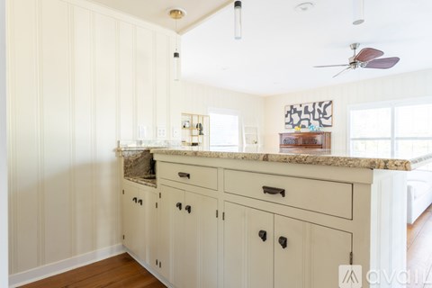 A kitchen with white cabinets and a marble countertop.