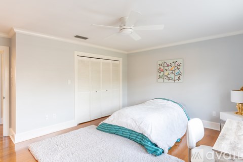 A bedroom with a white bed and a ceiling fan.