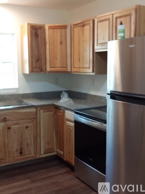 A kitchen with wooden cabinets and a stainless steel refrigerator.