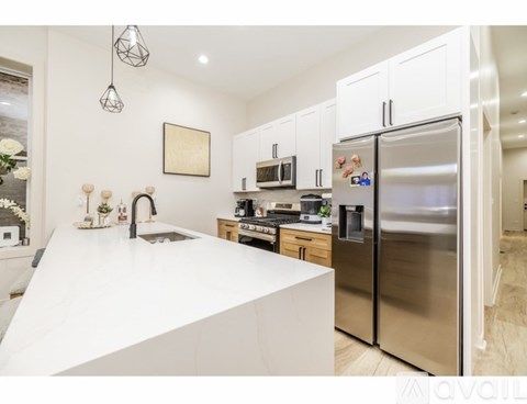 A modern kitchen with a white countertop and stainless steel appliances.