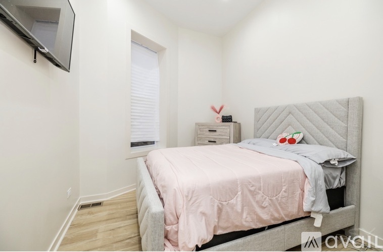 A bedroom with a bed, a nightstand, and a TV mounted on the wall.