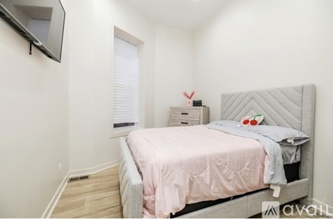 A bedroom with a bed, a nightstand, and a TV mounted on the wall.