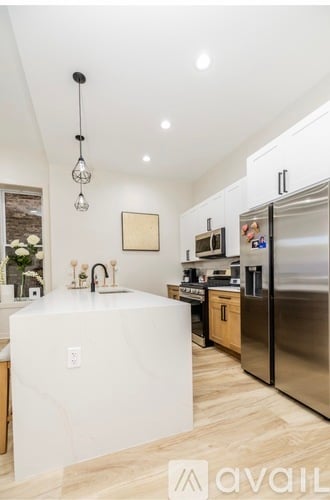 A modern kitchen with a white marble island and stainless steel appliances.