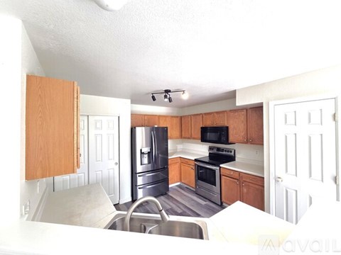 A kitchen with wooden cabinets and a black microwave.