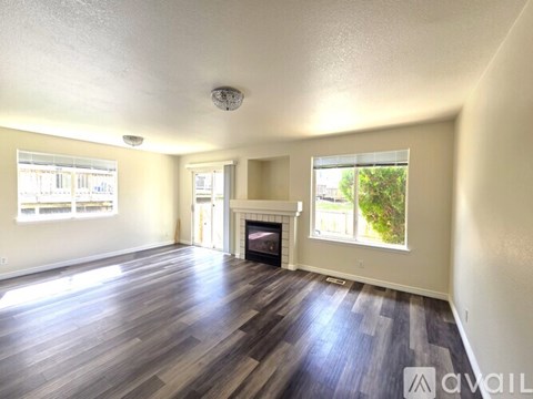 A spacious living room with wood flooring and a fireplace.
