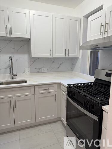 A kitchen with white cabinets and a black stove top oven.
