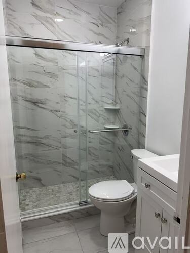 A bathroom with a marble shower and toilet.