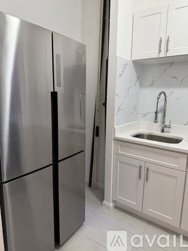 A kitchen with a stainless steel refrigerator and white cabinets.