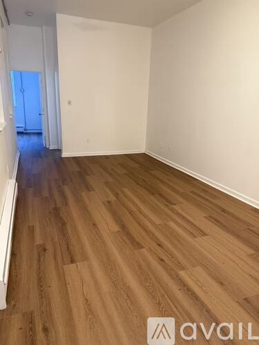 A room with wooden flooring and white walls.