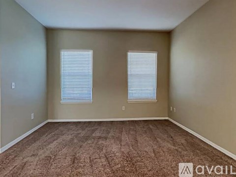 A room with two windows and carpeted flooring is available for rent.