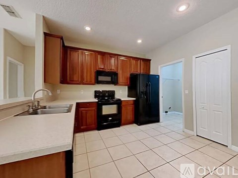A kitchen with brown cabinets and black appliances.