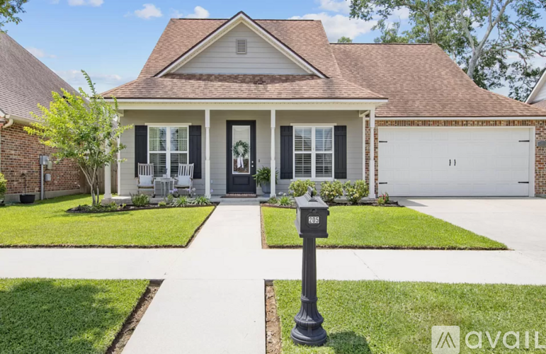 A house with a black front door and a mailbox on the lawn.