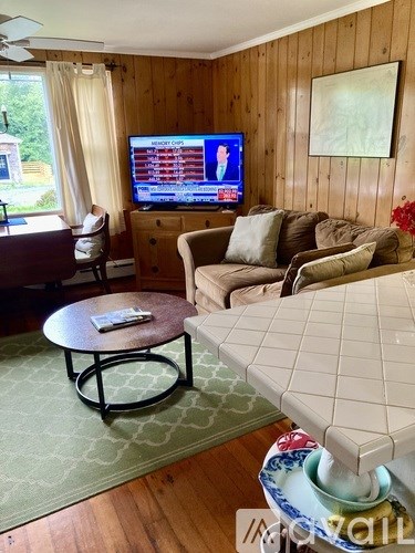 A living room with a TV, a couch, a chair, and a coffee table.