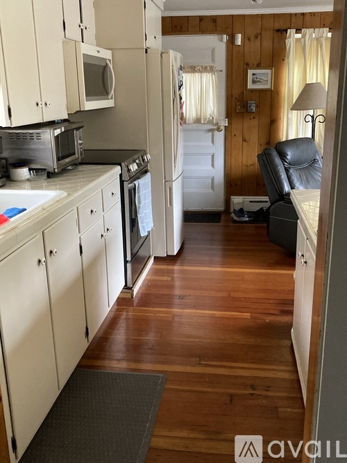 A kitchen with wooden floors and white cabinets.