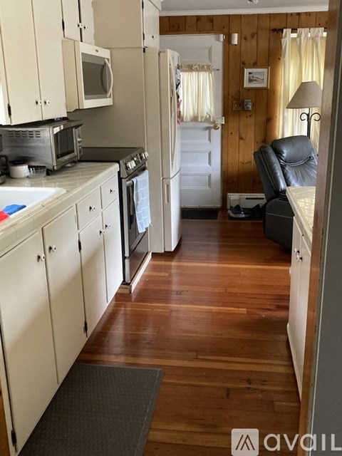 A kitchen with wooden floors and white cabinets.