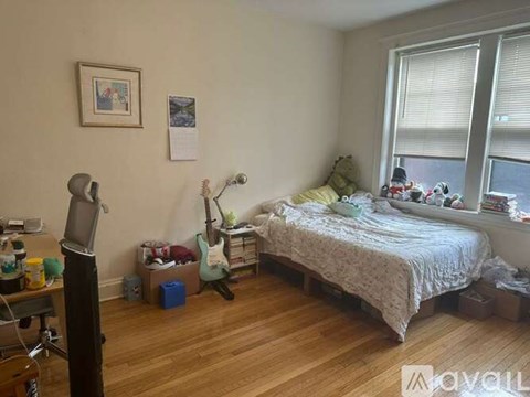 A bedroom with a bed, desk, chair, and window.