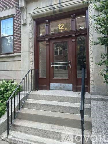 Steps leading to a brown door with a glass window and a metal railing.