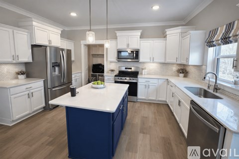 A kitchen with white cabinets and a blue island.