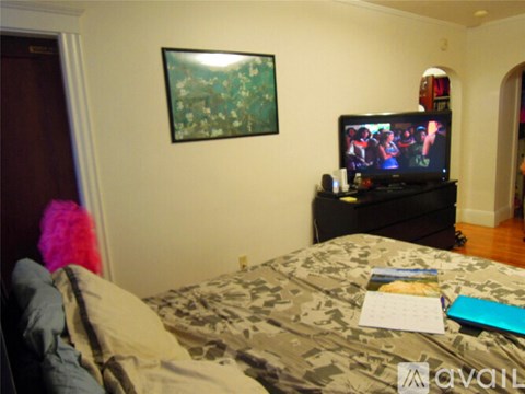 A bedroom with a bed, a television, and a painting on the wall.